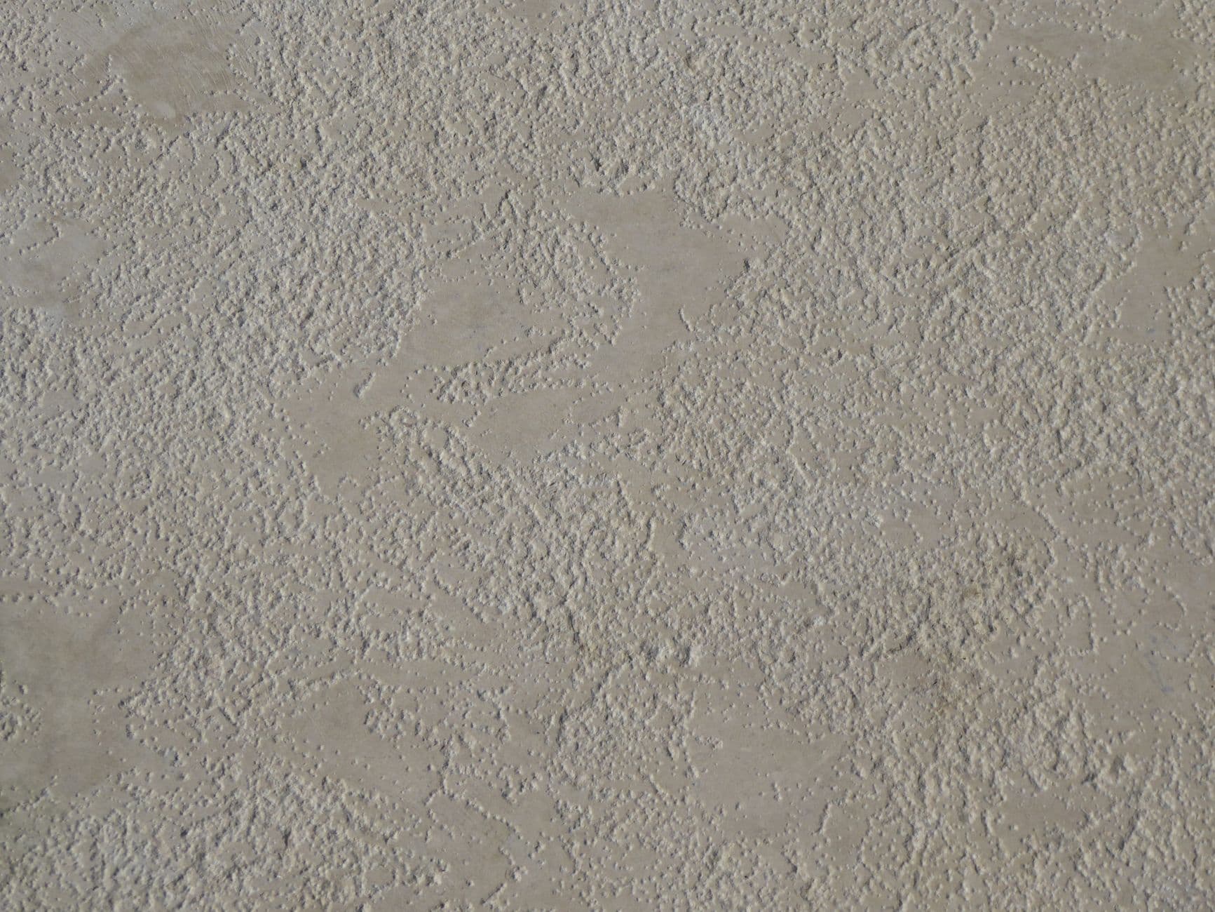 Beige muur met een fijne korrelstructuur en enkele platgestreken plekken